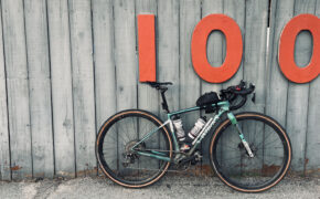 Bicycle leaning against a wall with large 100 address numbers.