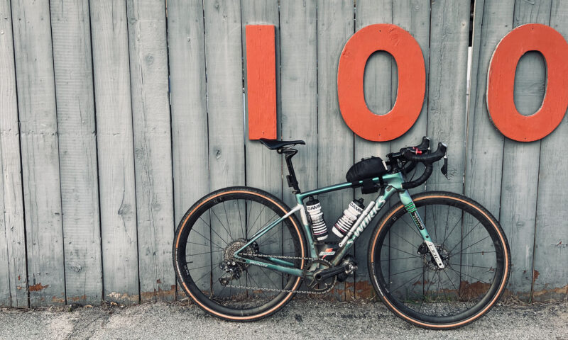 Bicycle leaning against a wall with large 100 address numbers.