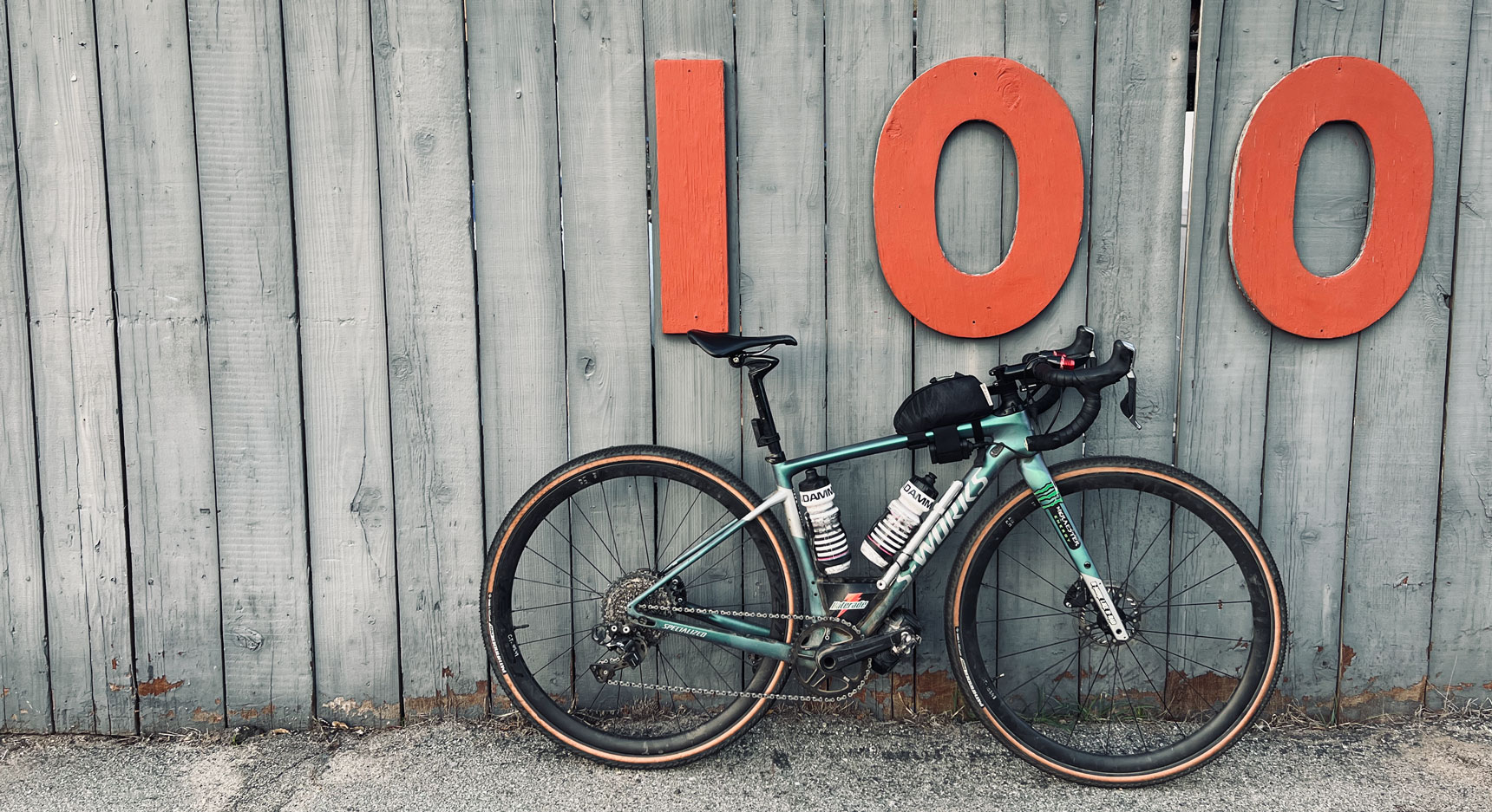Bicycle leaning against a wall with large 100 address numbers.